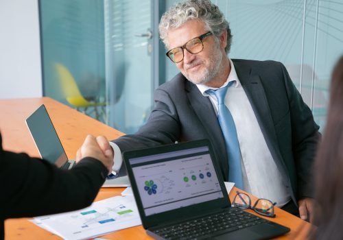 grey-haired-caucasian-businessman-handshaking-smiling